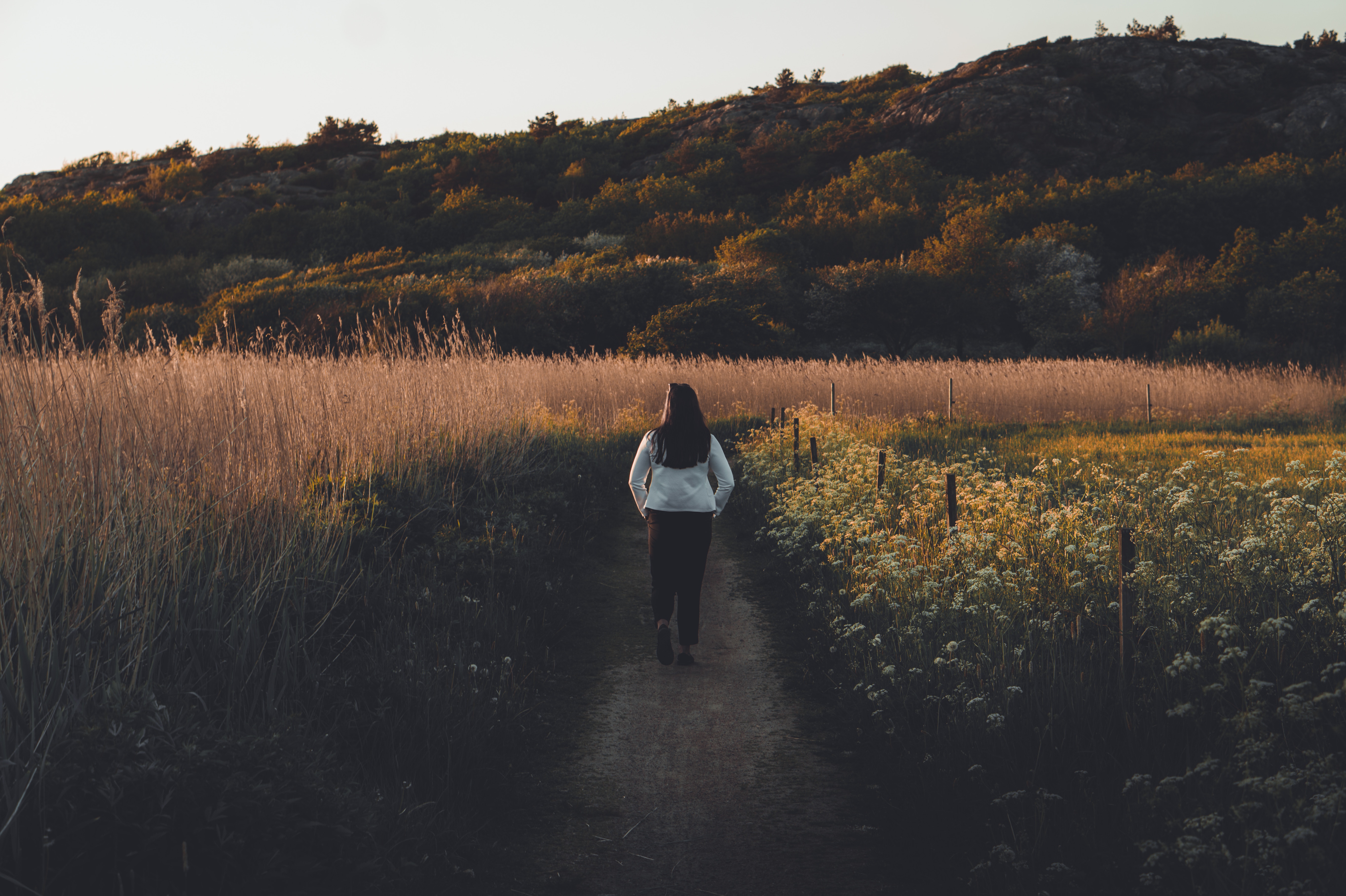 woman walking down path through field