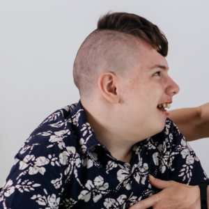 A young man with autism smiles at his caregiver.